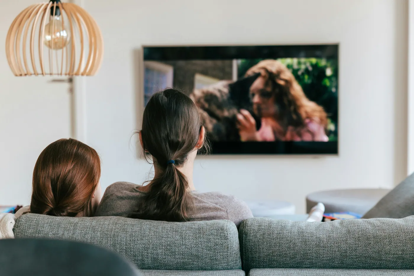 A mother and child watching television together on their sofa